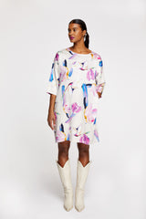 A woman wearing R/H Studio Square Long Dress in the light Rain Dance print with white boots.