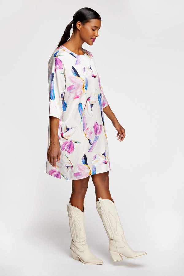 A woman wearing R/H Studio Square Long Dress in the light Rain Dance print with white boots.